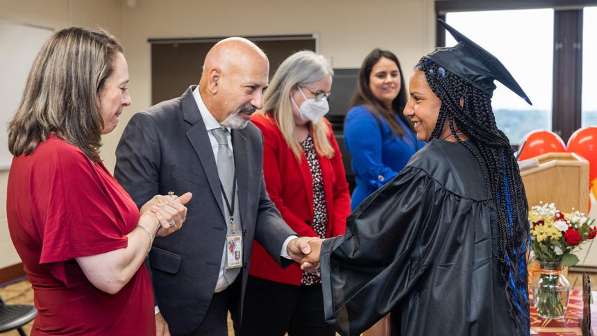 HiSET Graduate in cap and gown shaking hands